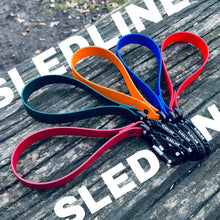 Biothane dog leads in blue, orange, teal, and red, displayed outdoors on wood