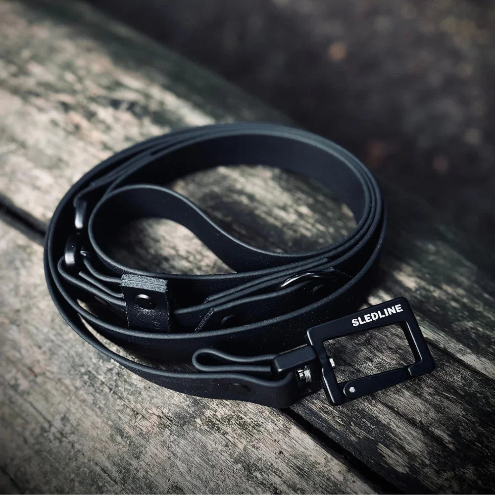 Black Biothane dog lead with strength tested hardware on rustic wooden surface