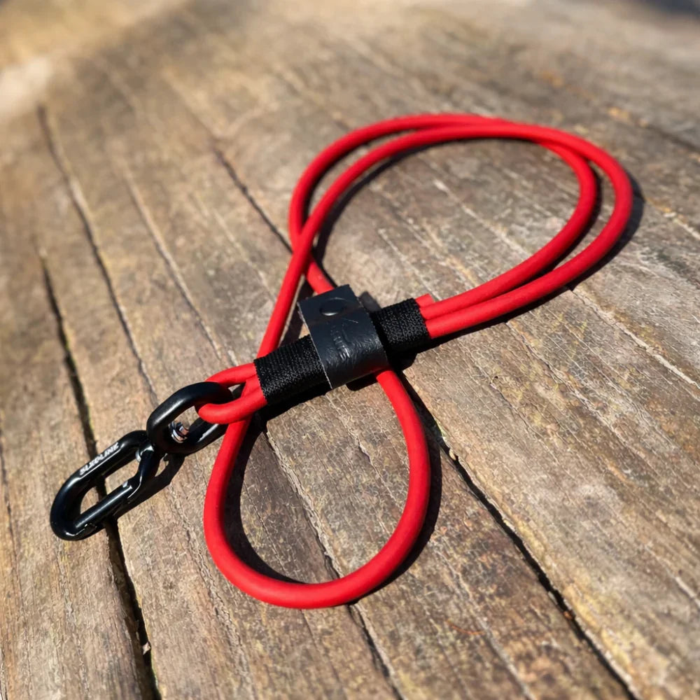 Red rPET rope dog lead with Biothane accents and black clip on wooden surface