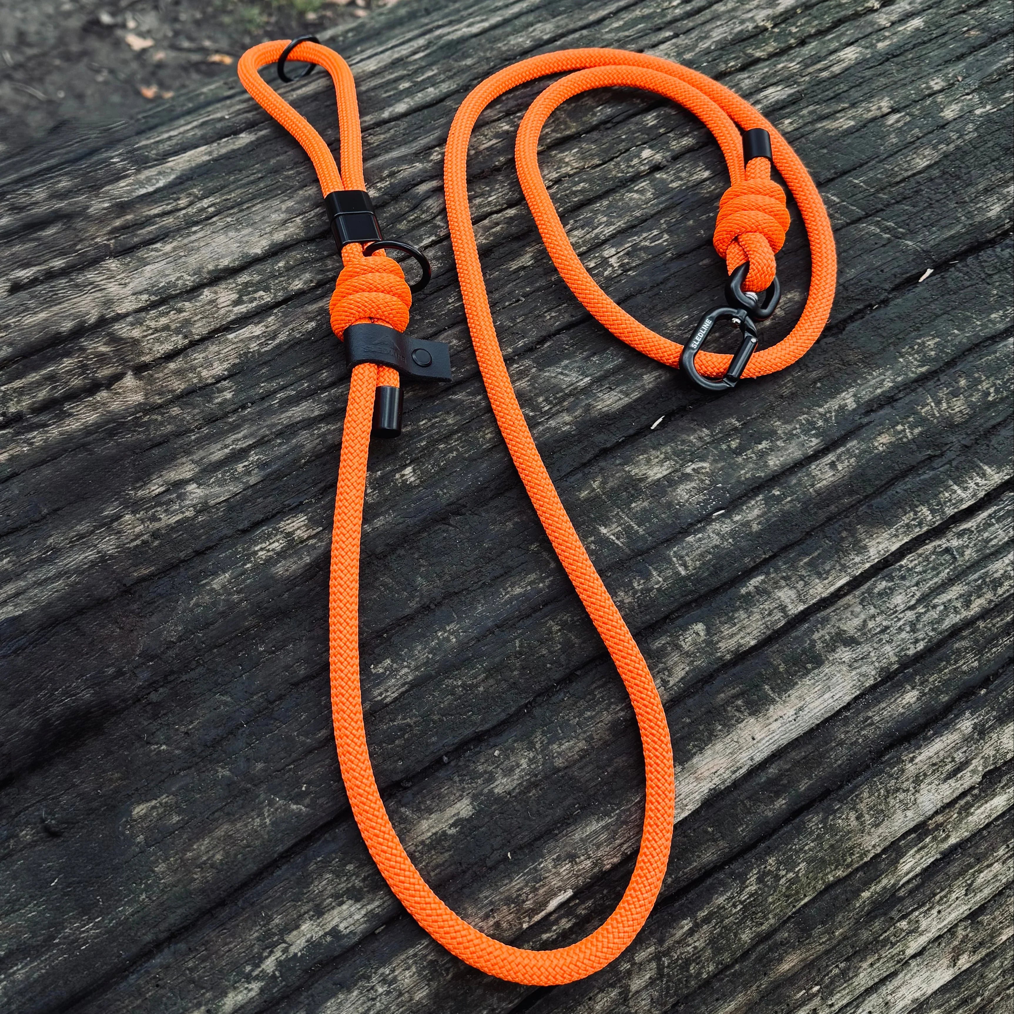 orange rope dog lead with black hardware presented on a log
